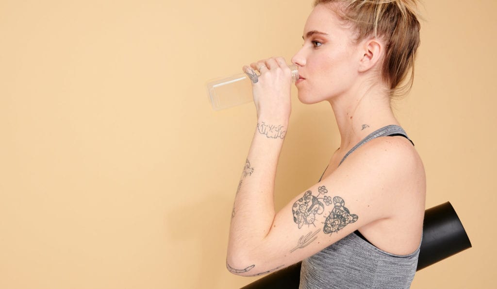 CBD water: what are the benefits of CBD-infused water? Woman drinking CBD water after doing yoga